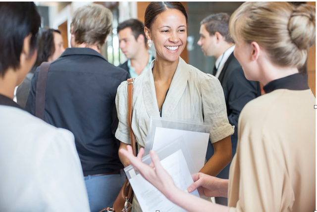 A woman making conversation while networking, holding papers